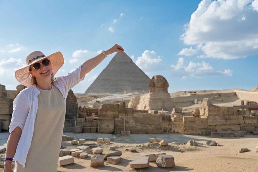 A person in a hat and dress pointing at the Great Pyramid of Giza. 5