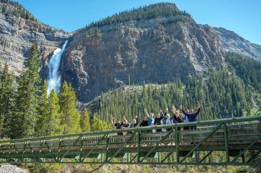 Un gruppo di persone su un ponte con vista su una cascata. 1