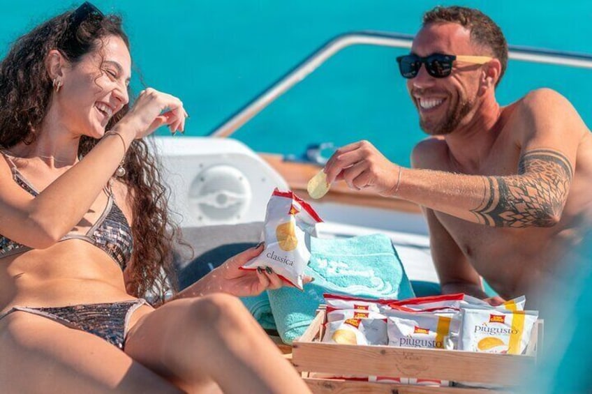 Two people on a boat, one holding a snack packet. 2