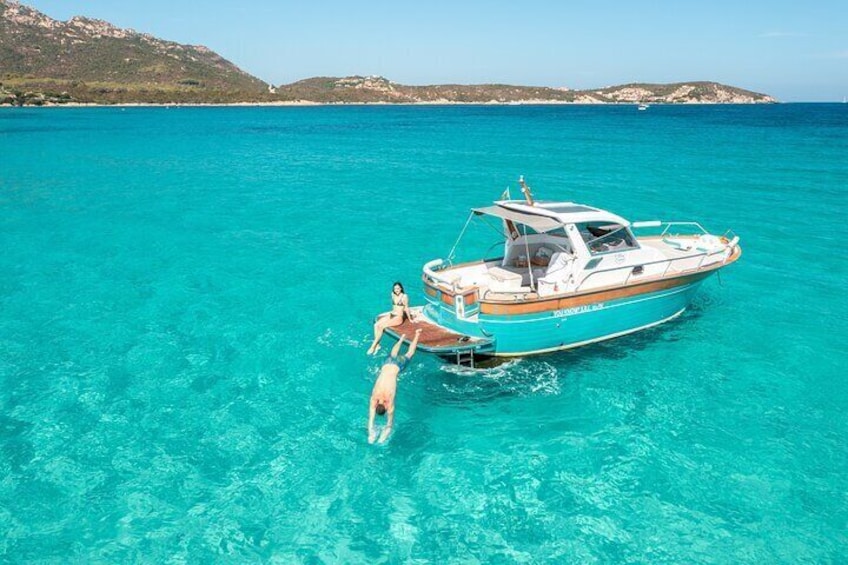A boat with two people on a turquoise sea with clear water. 5