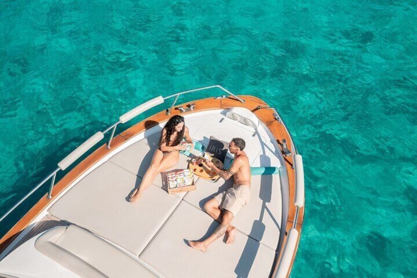 A boat with two people on deck, surrounded by clear turquoise water. 1