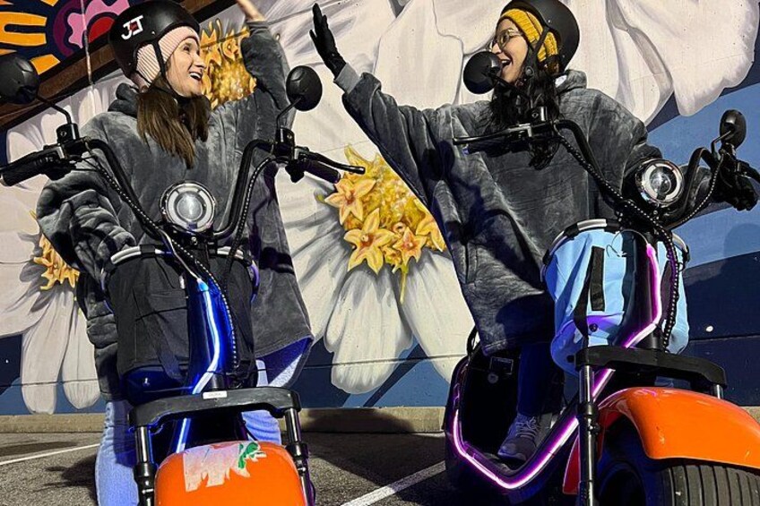 Twee personen op scooters, waarvan één wijst en de ander lacht. 5