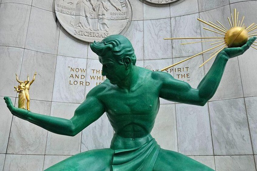 A green statue of a figure holding a golden object, with inscriptions on the wall behind. 3