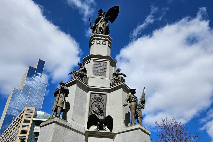 Un monument agrémenté de statues, d’une plaque commémorative et, en arrière-plan, d’un bâtiment moderne. 3