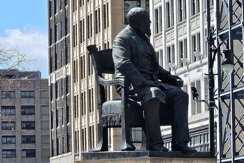 A statue of a seated man in a suit on a bench. 2