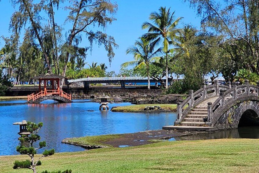 A stone bridge over water, a small pavilion, and palm trees. 3