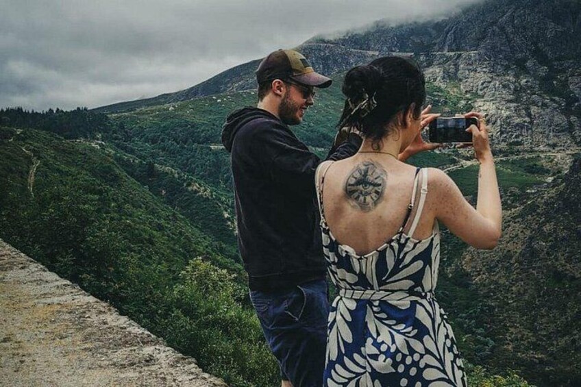A couple taking a photo of a mountainous landscape. 2