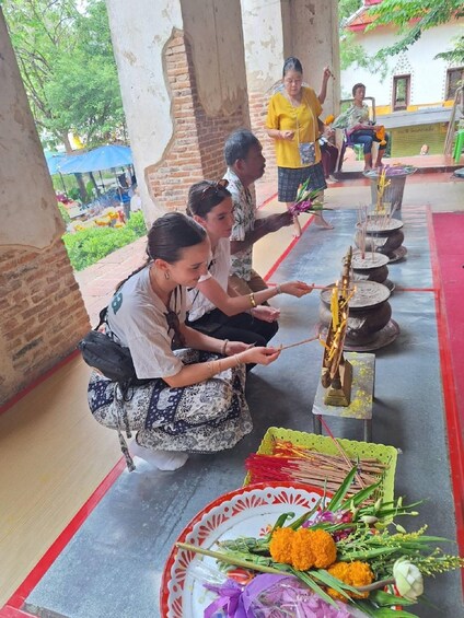 A group of people performing a ritual with incense sticks and offerings at a temple. 1