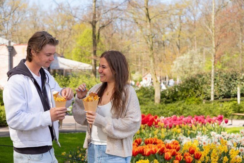 Two people eating ice cream cones in a park with colorful flowers and trees. 3