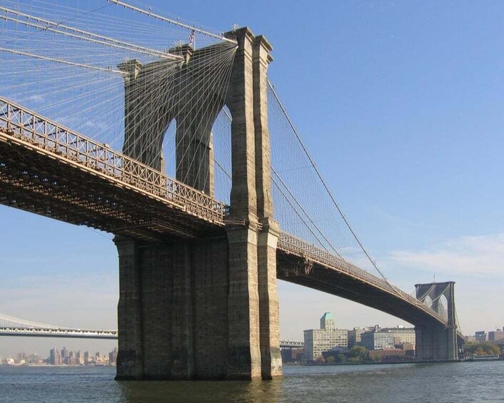 A large suspension bridge with tall towers and cables, spanning a body of water with a city skyline in the background. 2