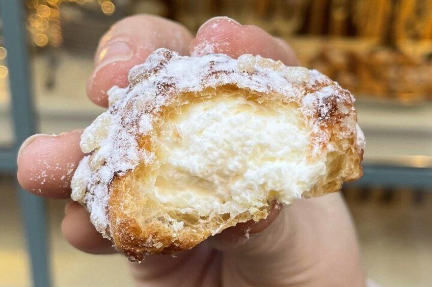 A hand holding a pastry with a powdered sugar coating. 2