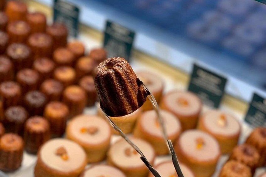 A close-up of a caramelized dessert on a stick, with a blurred background of similar desserts. 1
