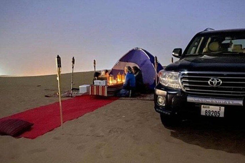 Cacampamento en el desierto con una tienda de campaña, una alfombra roja y un SUV Toyota. 3