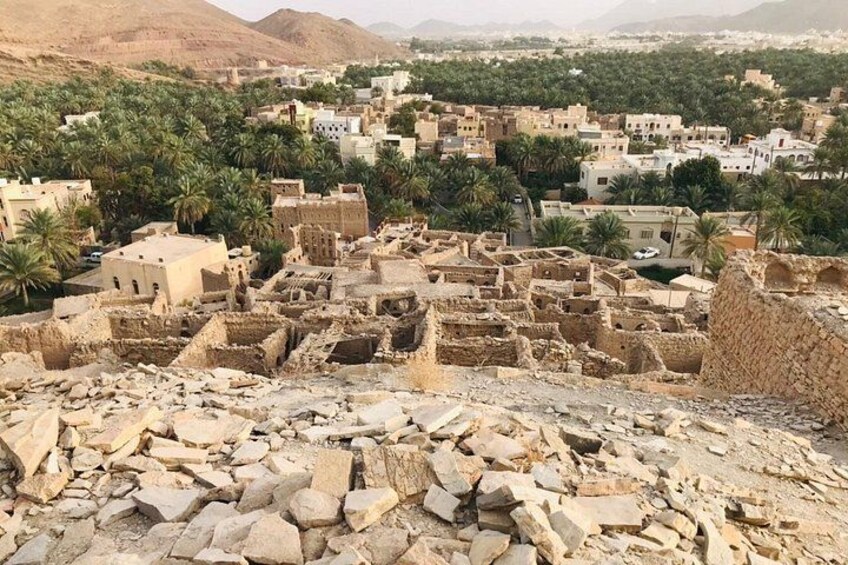 A historical site with ancient ruins and modern buildings, surrounded by palm trees and mountains. 4