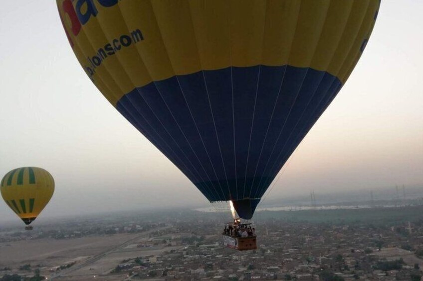 A hot air balloon with a yellow and blue design flying over a cityscape. 5