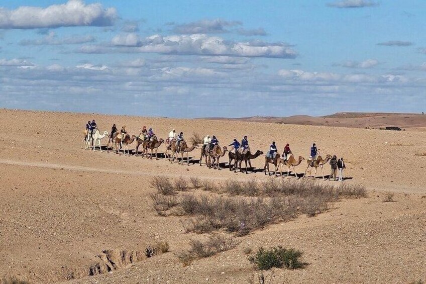 A group of people riding camels in a desert landscape. 5