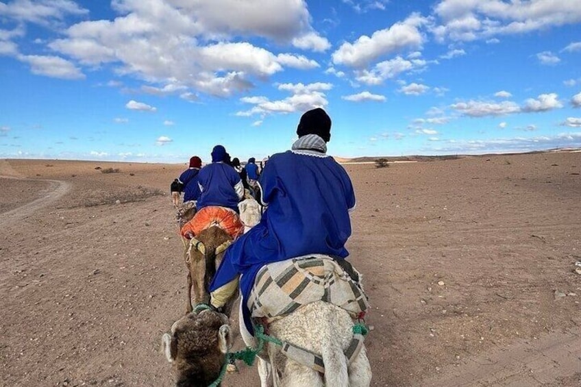 A group of people riding camels in a desert landscape. 3