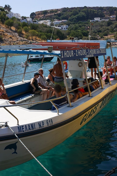 A boat with people on board, a sign advertising sea cruises, and a coastal landscape with buildings. 2