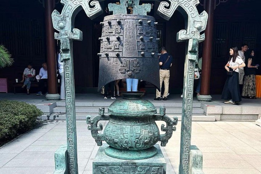 Een bronzen beeld met ingewikkelde details, een grote vaas en een decoratieve boog. 3