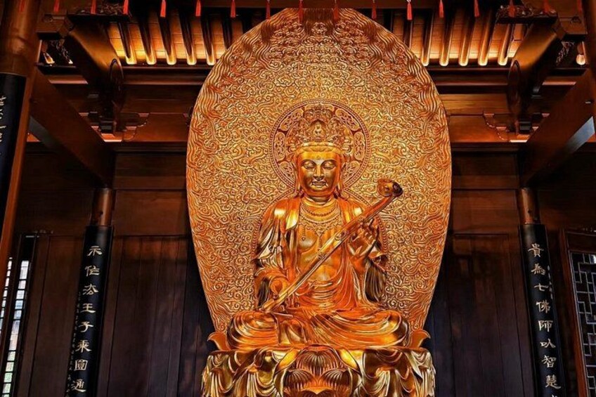 A golden Buddha statue with intricate patterns, seated in a traditional posture, surrounded by ornate architecture. 3