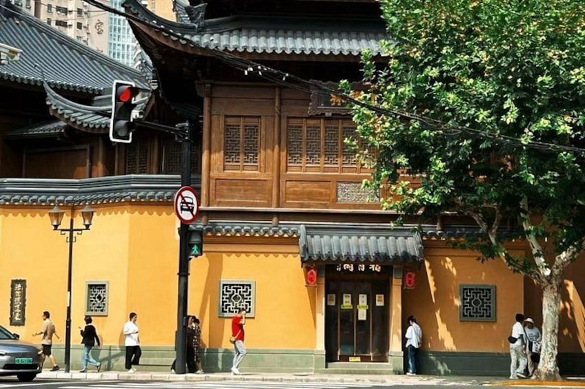 A traditional building with a yellow facade, a red traffic light, and pedestrians walking by. 2