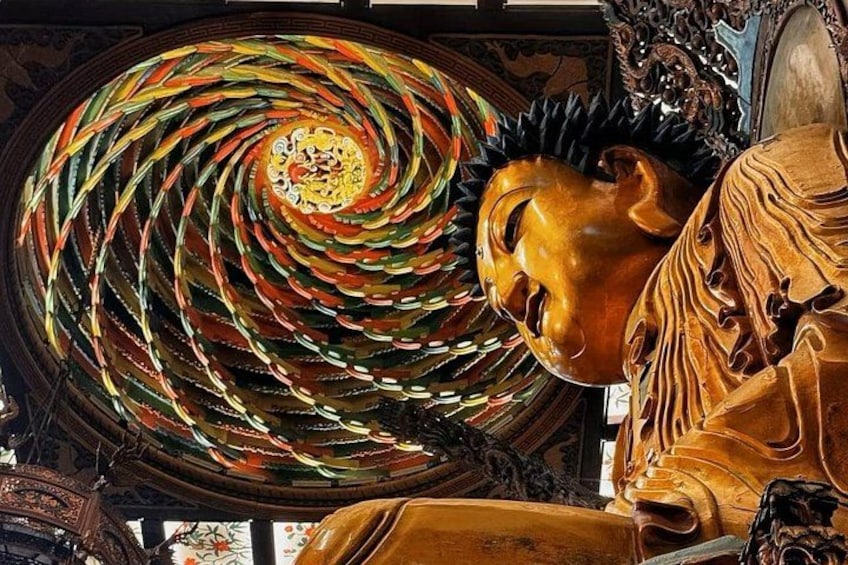A large wooden sculpture with a spiral design and a face. 4