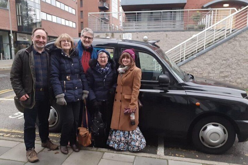 Un grupo de personas de pie junto a un coche negro en una calle de la ciudad. 2