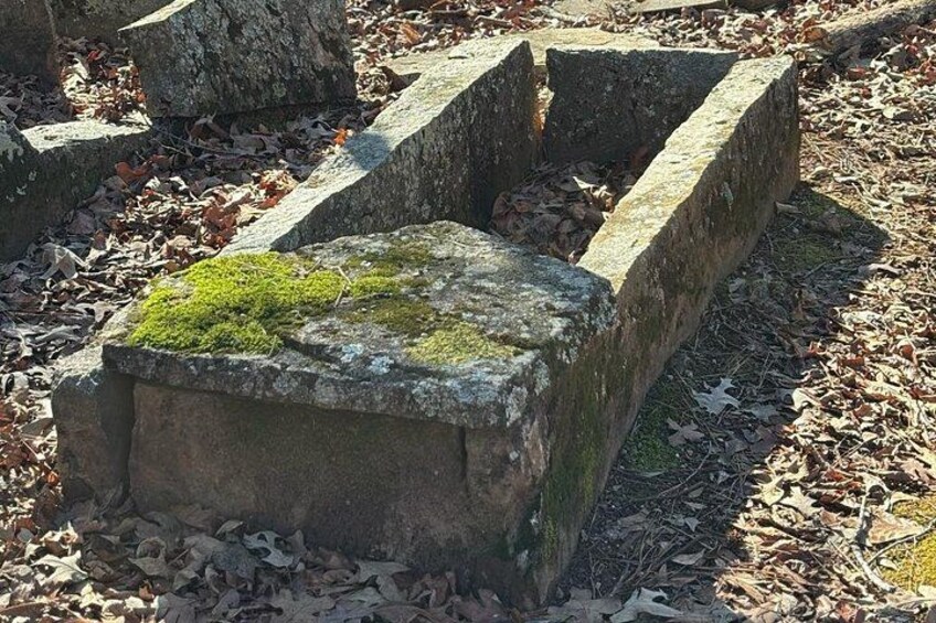 A stone structure with moss growth, surrounded by fallen leaves. 2