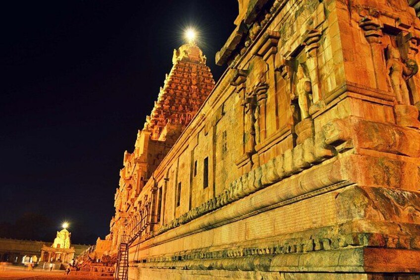 A temple with intricate carvings and a large illuminated spire at night. 2