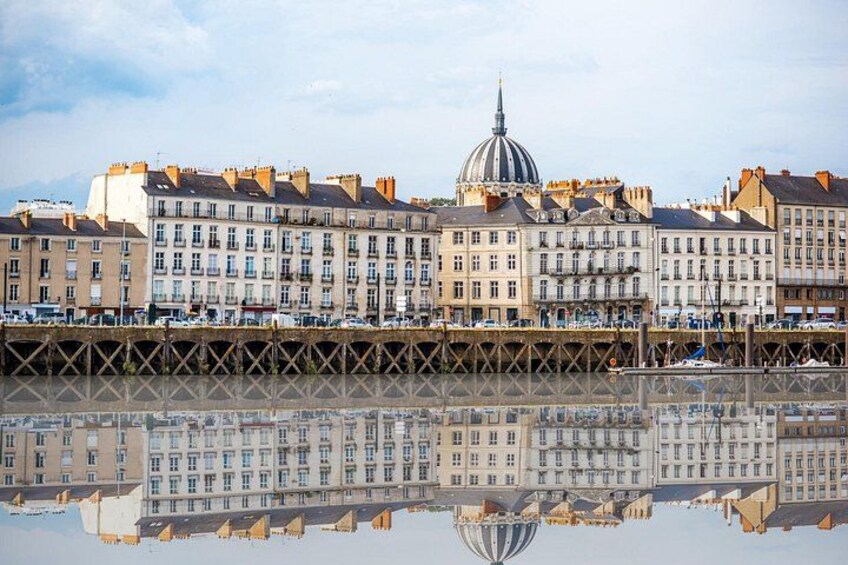 A waterfront with buildings, a bridge, and a reflection in the water. 2