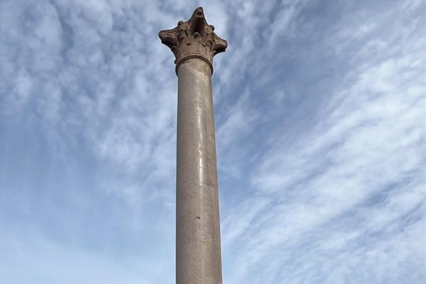 Een hoge, slanke zuil met een decoratieve bovenkant tegen een bewolkte lucht. 4
