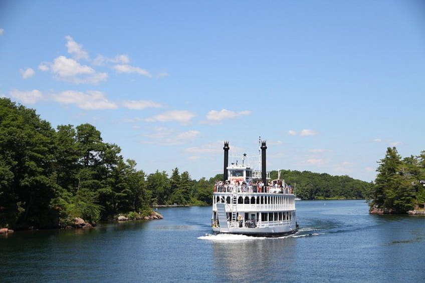 A multi-deck riverboat with passengers, surrounded by lush greenery and calm water. 3