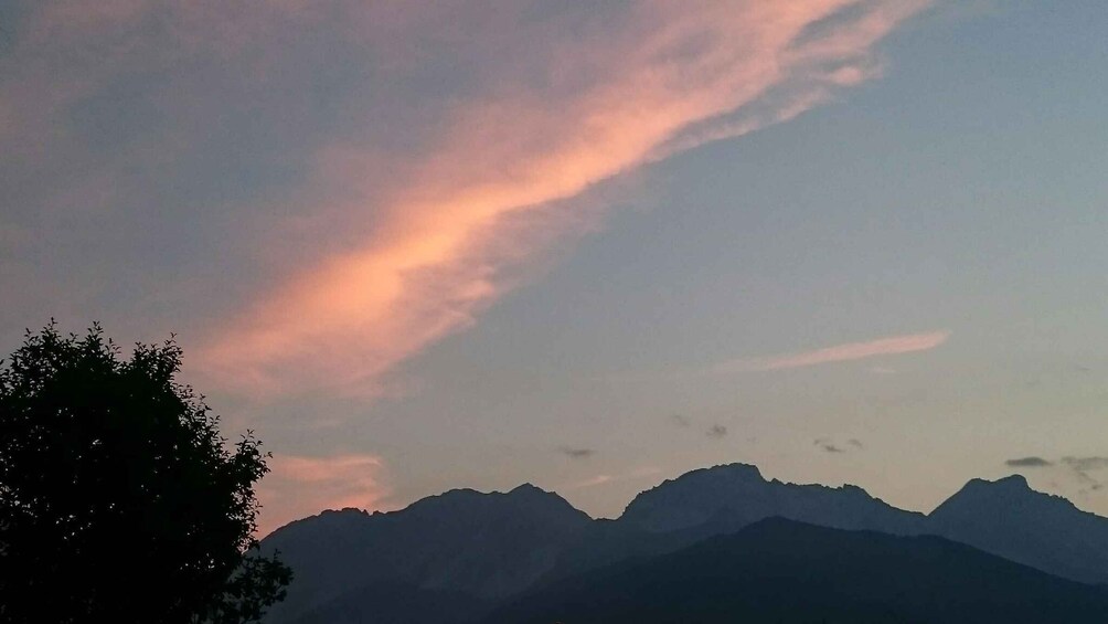 A mountain range silhouetted against a sky with pink and purple clouds. 2