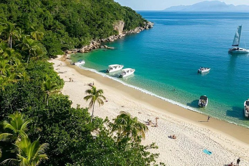 Una spiaggia con barche, palme e una costa rocciosa. 3