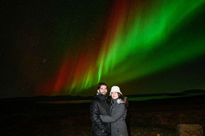 A couple standing under a night sky with the aurora borealis. 5