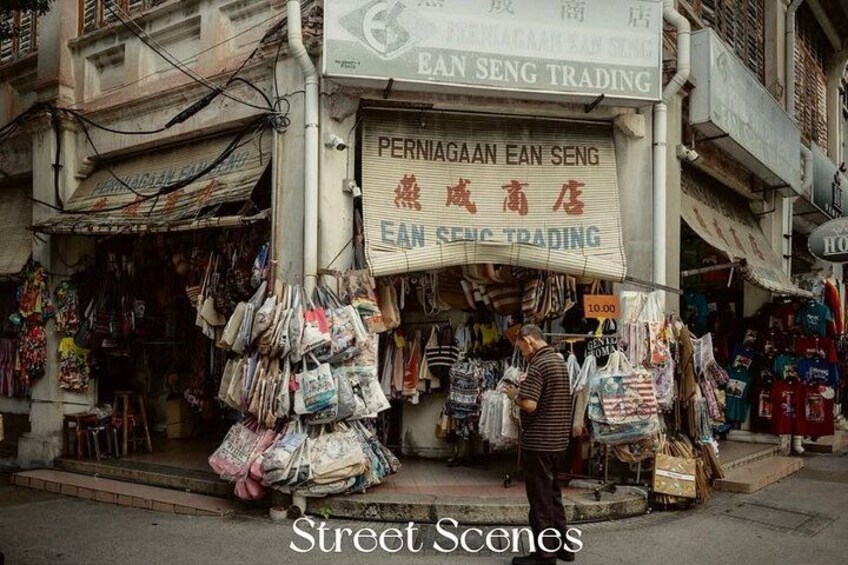 Une scène de rue avec un magasin appelé « PERNIAGAAN EAN SENG TRADING » où sont exposés divers produits. 5