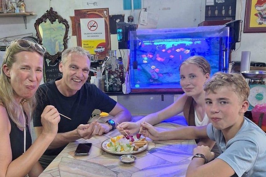 A family sitting around a table with a fish tank in the background. 2