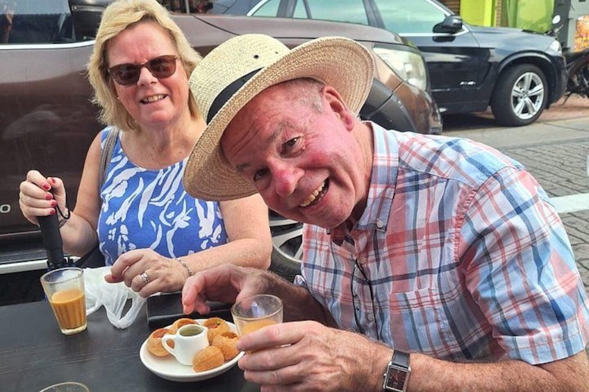 Twee personen zitten aan een tafel met eten en drinken. 1