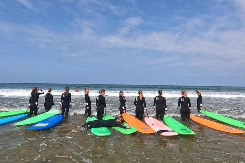 A group of people in wetsuits standing on a beach with surfboards. 2