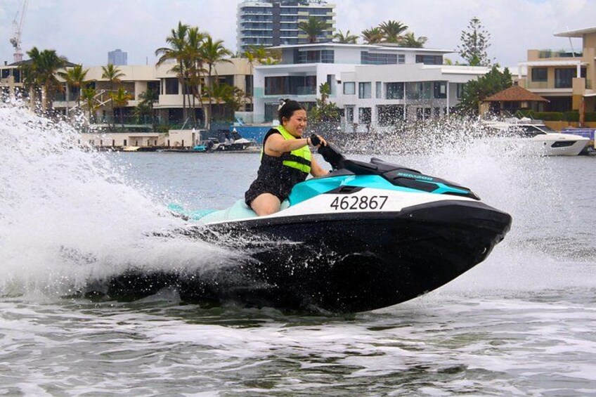 A person riding a jet ski on water with a cityscape in the background. 3