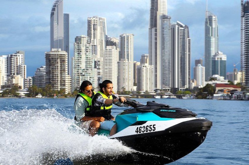 A jet ski with two people wearing life jackets, a city skyline in the background, and a body of water. 4
