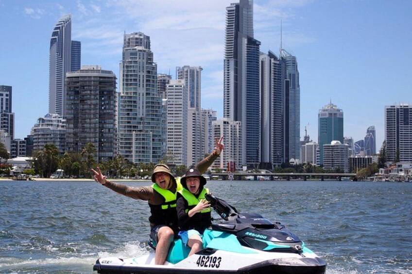 Two people on a jet ski with a city skyline in the background. 2