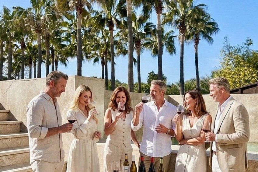 A group of people standing outdoors, holding wine glasses, with palm trees in the background. 4