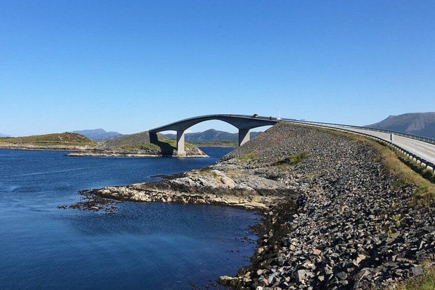 Un puente sobre el agua con una orilla rocosa. 2