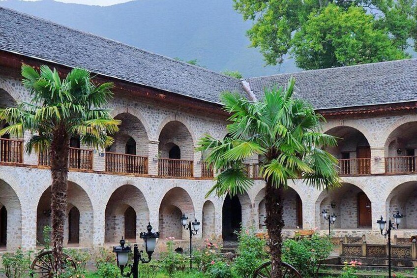 A courtyard with arched walkways, palm trees, and a building with a tiled roof. 5