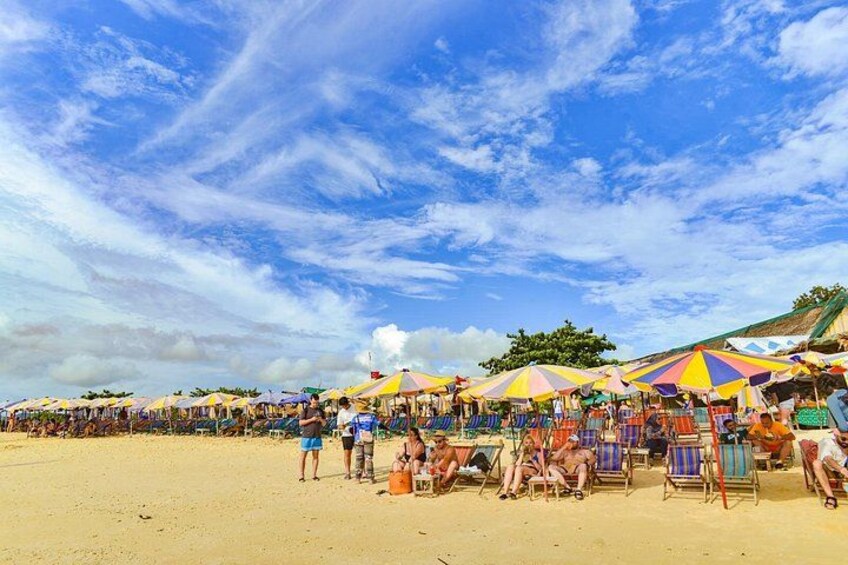 Una playa con sombrillas de colores y gente relajándose. 3