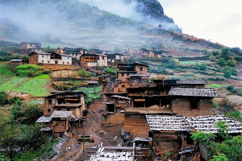 A village with traditional houses, a dirt road, and a mountainous backdrop. 4