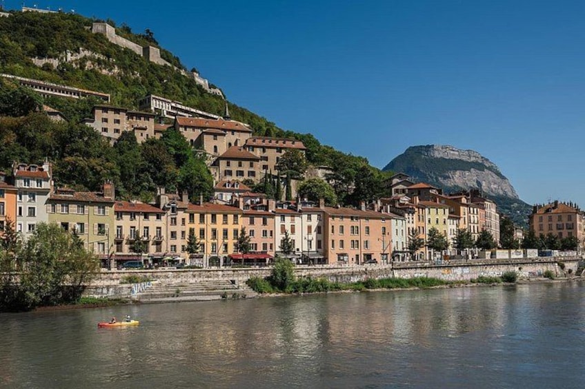 A riverside town with buildings, a bridge, and a hill with a fortification. 2