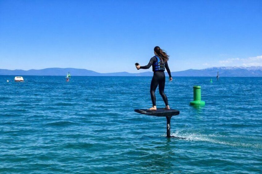 Una persona surfeando sobre una tabla en el océano, con montañas al fondo. 5