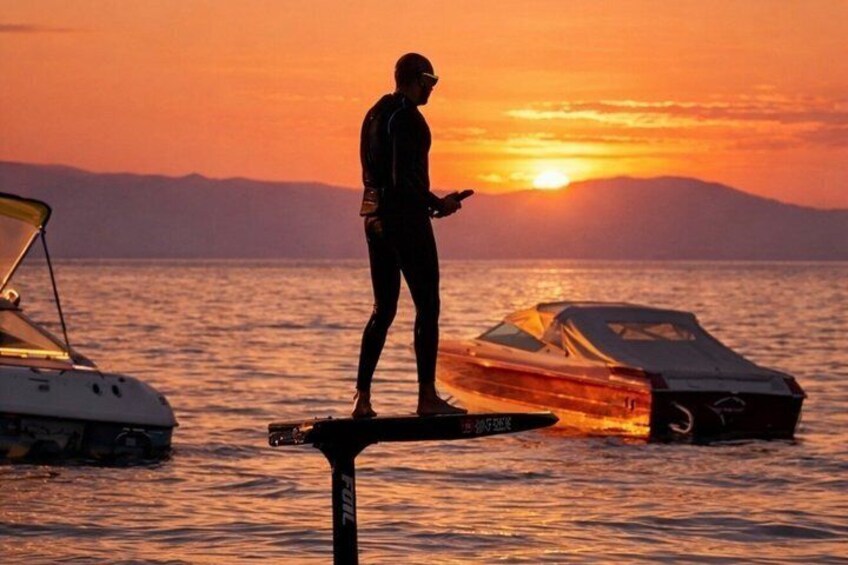 Una persona de pie en una tabla de remo con un barco al fondo durante la puesta de sol. 4